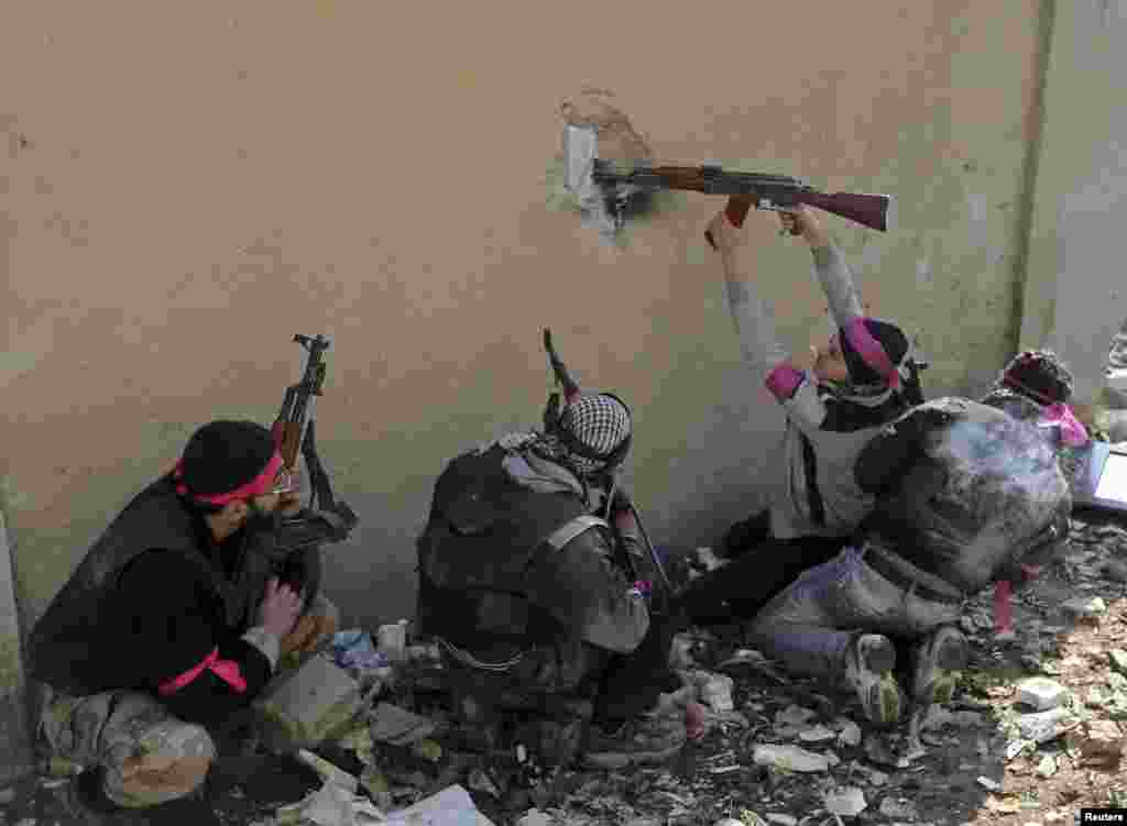 A Free Syrian Army fighter fires a rifle through a hole in a wall of a Syrian Army base moments before he was shot in the head by a sniper during heavy fighting in the Arabeen neighborhood of Damascus. (Reuters/Goran Tomasevic)