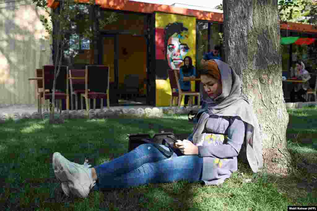 Before: A woman browses on her phone in the courtyard of a cafe in Kabul in August 2019.