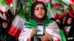 O femeie ține în mână un telefon pe care se vede fotografia unei persoane ucise, în timpul unei ceremonii din a 40-a zi de doliu pentru victimele din timpul protestelor antiguvernamentale din Iran, la Teheran, pe 17 februarie 2026.