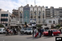 People load items looted from the Iranian Embassy onto trucks in Damascus on December 8.