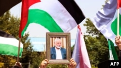 People hold up the Palestinian flag and a portrait of assassinated Hamas chief Ismail Haniyeh during a rally at Tehran University on July 31.