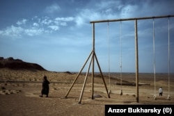 A set of swings in the dusty expanse of the desert of Karakalpakstan in the north of Uzbekistan.