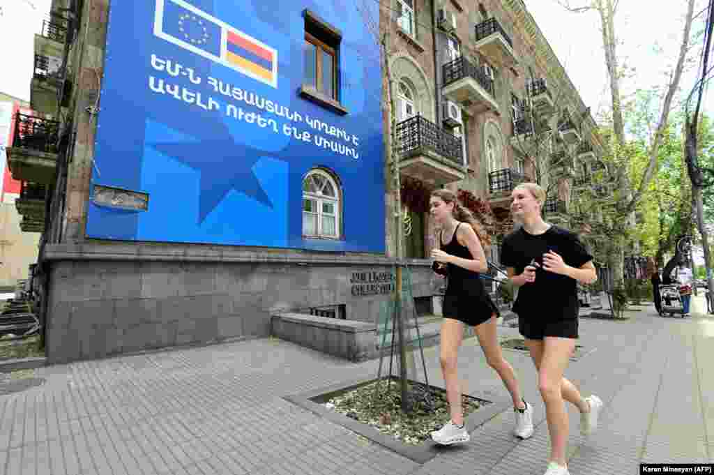 Joggers on May 2 pass a poster in central Yerevan promoting the summit.