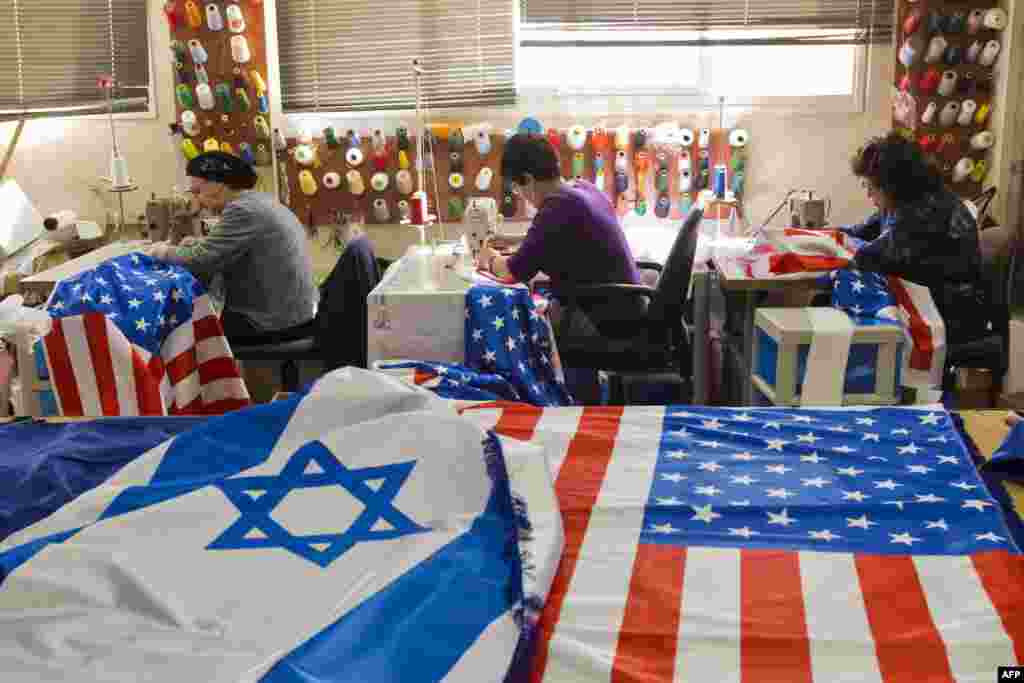 Employees sew Israeli and U.S. flags in preparation for the upcoming visit of U.S. President Barack Obama in the town of Kfar Saba, Israel. Obama&#39;s three-day visit to Israel and the Palestinian territories will begin on March 20, Israel said. (AFP/Jack Guez)