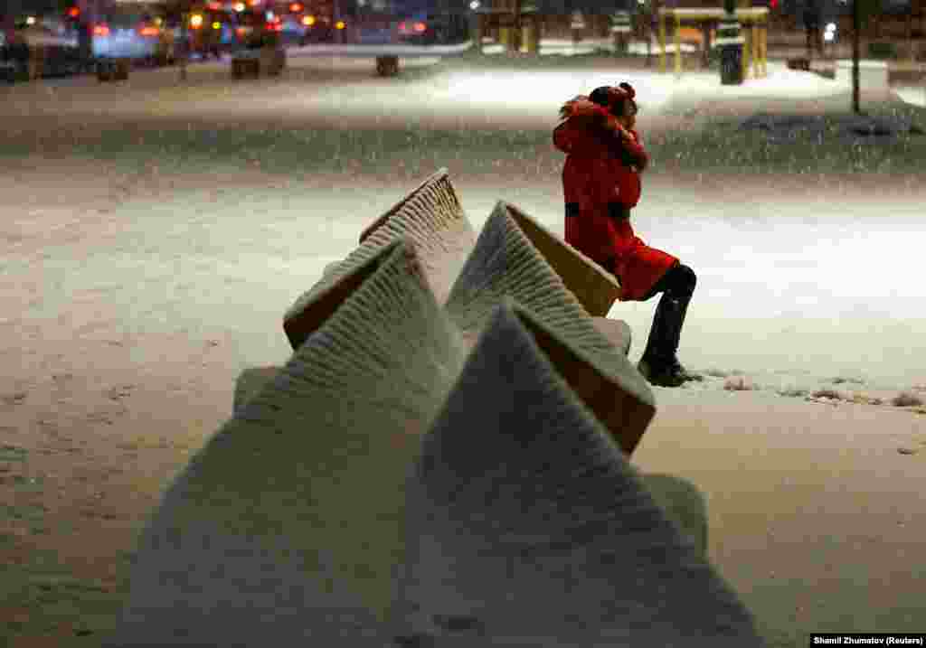 A woman sits on a bench as she poses for a picture during a snowfall in Almaty, Kazakhstan, on February 6. (Reuters/Shamil Zhumatov)