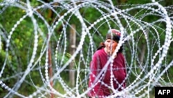 A woman looks through 1.2-meter-high coils of razor wire that divide the Russian-backed breakaway territory of South Ossetia from Georgian-controlled land in village of Khurvaleti.