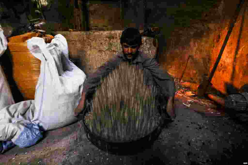 Афганский рабочий готовится жарить семена на фабрике в Герате.