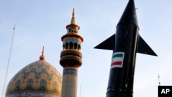 Iranski demonstranti nose model projektila dok se u pozadini vidi minaret i kupola džamije tokom antiizraelskog skupa u Teheranu 15. aprila.