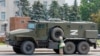 An elderly woman looks at an armored truck belonging to pro-Russian troops parked near Ukraine's former regional council building in the Russia-controlled city of Kherson on July 25.