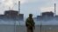 A soldier with a Russian flag on his uniform stands guard near the Zaporizhzhya nuclear power plant outside the Russian-controlled city of Enerhodar on August 4. 