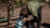 A woman drinks clean water from a canister she just filled up in the eastern city of Slovyansk.