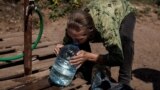 A woman drinks clean water from a jug in the eastern city of Slovyansk.