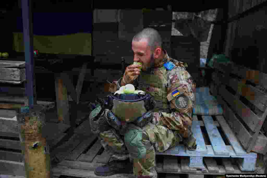 A member of the Ukrainian National Guard eats apples during a lull in fighting at a position near the front line in the Kharkiv region on August 3.&nbsp;