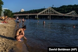 Sunbathers gather along the Dnieper River in Kyiv on July 31, despite the constant threat of rocket attacks.