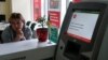 An employee sits next to a payment terminal out of order at a branch of Ukraine's state-owned Oschadbank in Kyiv on June 27.