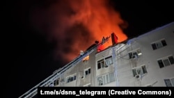 Firefighters work to extinguish a blaze at a residential building hit by a Russian drone attack in Mykolayiv, Ukraine, early on January 22.