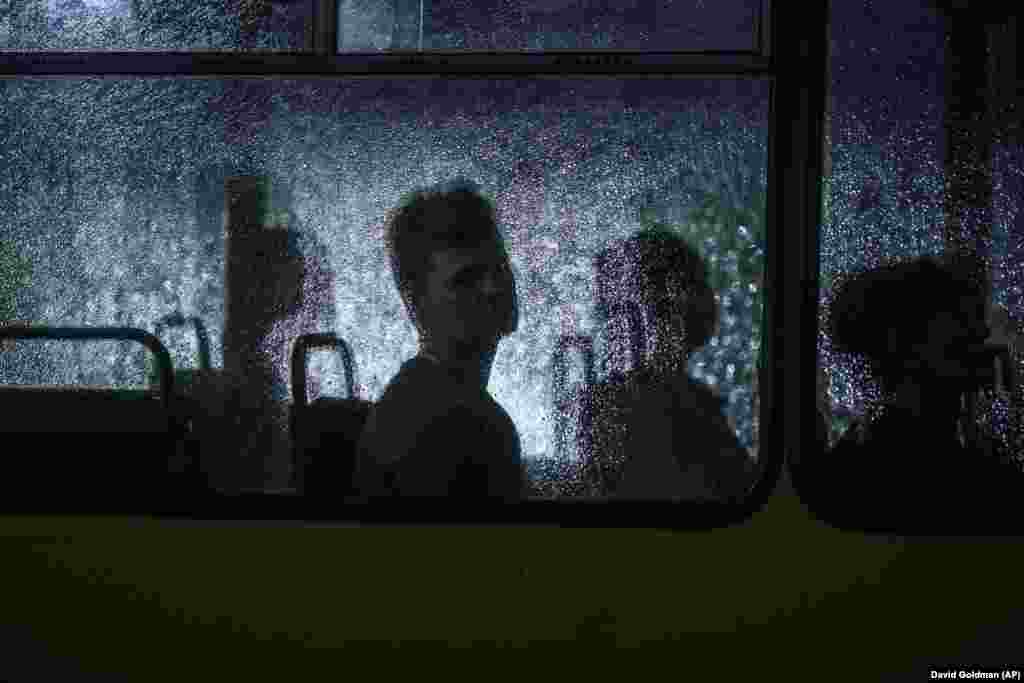 A passenger looks out of a bus window during a rain shower in Dnipro, Ukraine.
