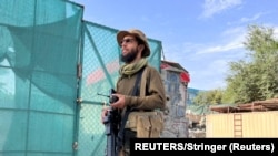 یک نیروی امنیتی حکومت طالبان در نزدیک خانۀ در منطقه شیرپور شهر کابل که در آن رهبر شبکه القاعده هدف قرار گرفت، ایستاده است.