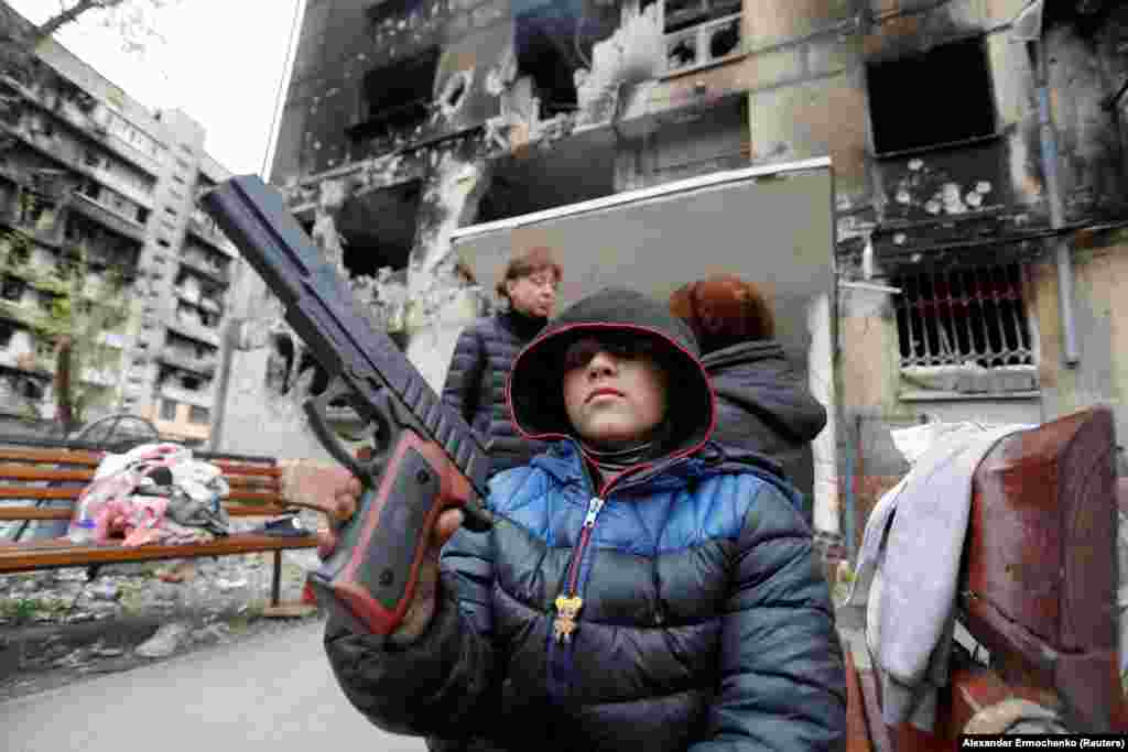 Sasha, 8, shows off a toy pistol in front of a heavily damaged apartment building in Mariupol on April 21.&nbsp;