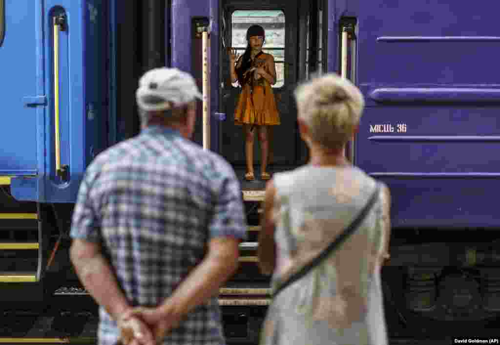 Another young girl waves goodbye to her grandparents on the evacuation train while holding her dog.