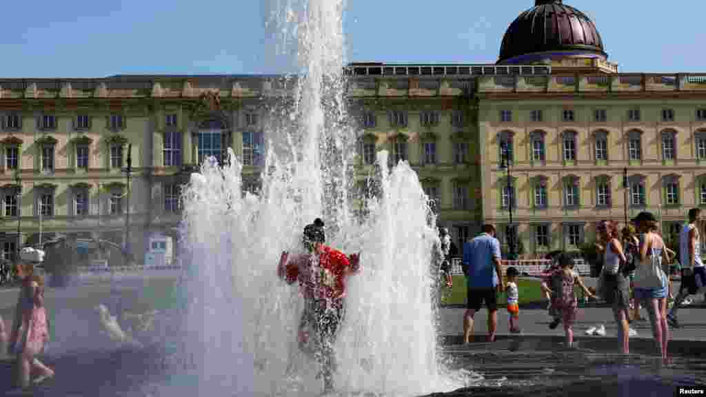 Egy nő szökőkútban fürdik Berlinben, Németországban 2022. július 19-én