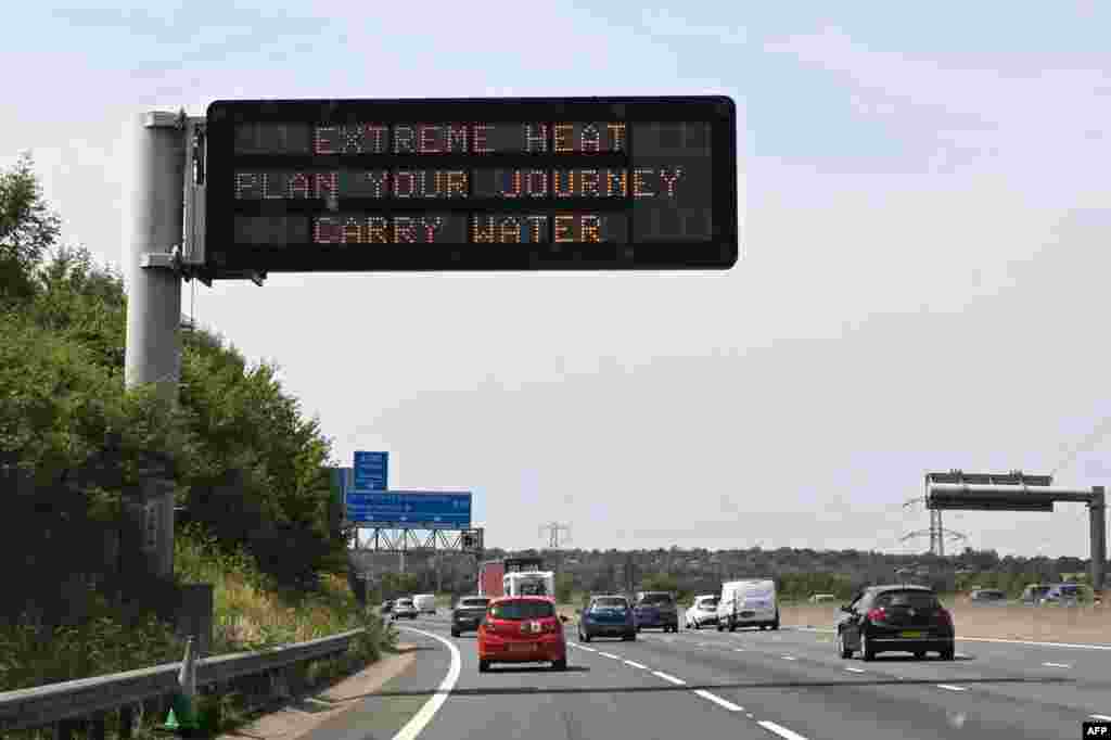 Un indicator rutier pe care scrie &bdquo;Căldură extremă, planificați-vă călătoria, transportați apă&rdquo; avertizează șoferii cu privire la valul de căldură prognozat pentru 18 și 19 iulie, pe autostrada M11, la nord de Londra, pe 17 iulie 2022.