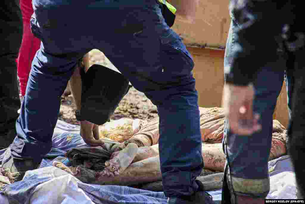 Rescuers inspect the body of a civilian killed in a Russian air strike on a social and cultural center in the city of Chuhuiv in Ukraine&#39;s Kharkiv region.