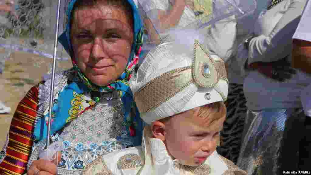 Žena drži dete u krilu, oboje su u svečanim tradicionalnim nošnjama. Inače, Gornje Ljubinje&nbsp;je naseljeno mesto u opštini&nbsp;Prizren&nbsp;na&nbsp;Kosovu. Selo ima oko 3.000 stanovnika i svi su bošnjačke nacionalnosti.&nbsp;