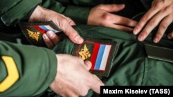 Призывники крепят шевроны на военную форму