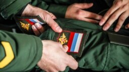 Призывники крепят шевроны на военную форму