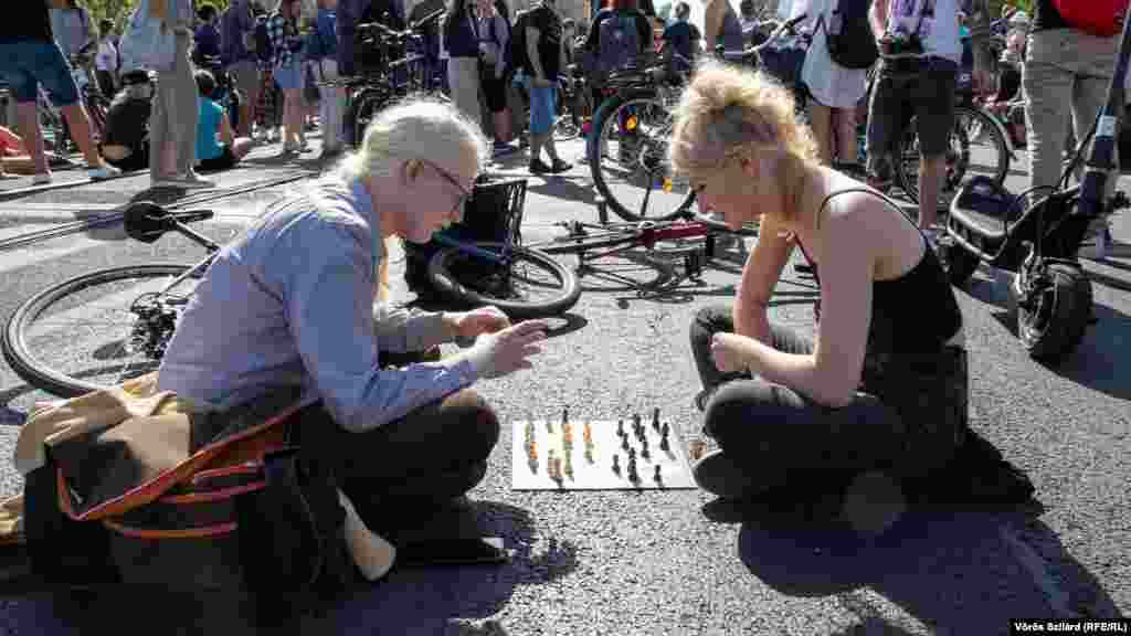 Doi curieri pe biciclete joacă șah blocând traficul pe Podul Margareta din Budapesta pe 18 iulie, la un protest contra modificării regimului fiscal simplificat cunoscut sub numele de KATA. Criticii spun că schimbările dăunează întreprinderilor mici și vor afecta sute de mii de oameni. (Voros Szilard, RFE/RL)