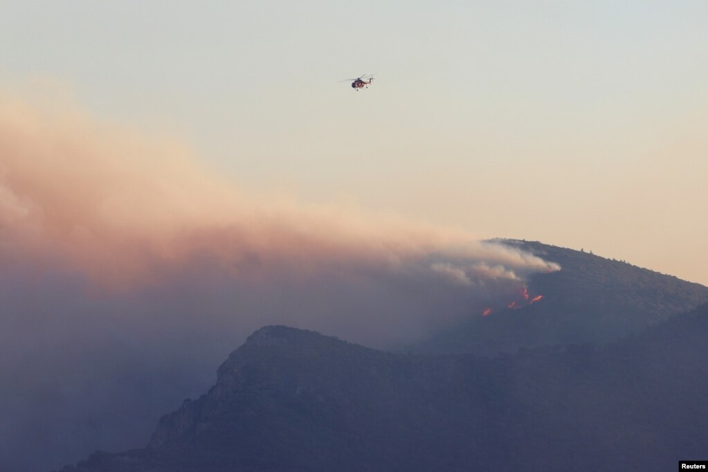 Një helikopter zjarrfikës fluturon mbi një zjarr në ishullin Samos, Greqi, 13 korrik 2022.