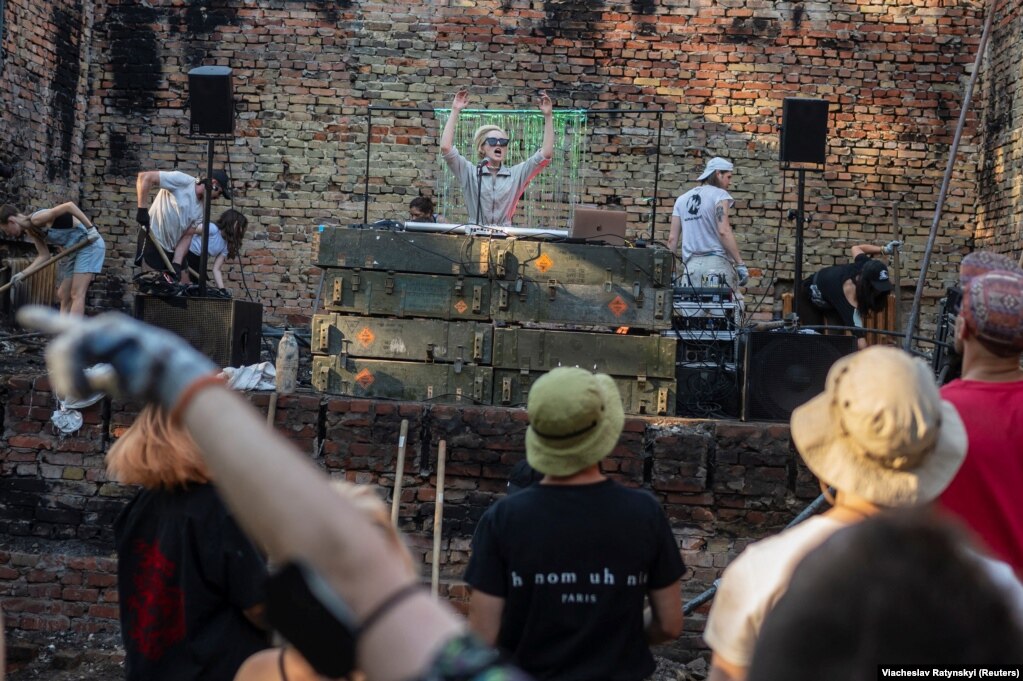 Një DJ lëshon muzikë, derisa shumë vullnetarë nga iniciativa "Riparojmë së Bashku" rindërtojnë një qendër kulturore që u shkatërrua nga një sulm me raketa ruse në fshatin Yahidne.