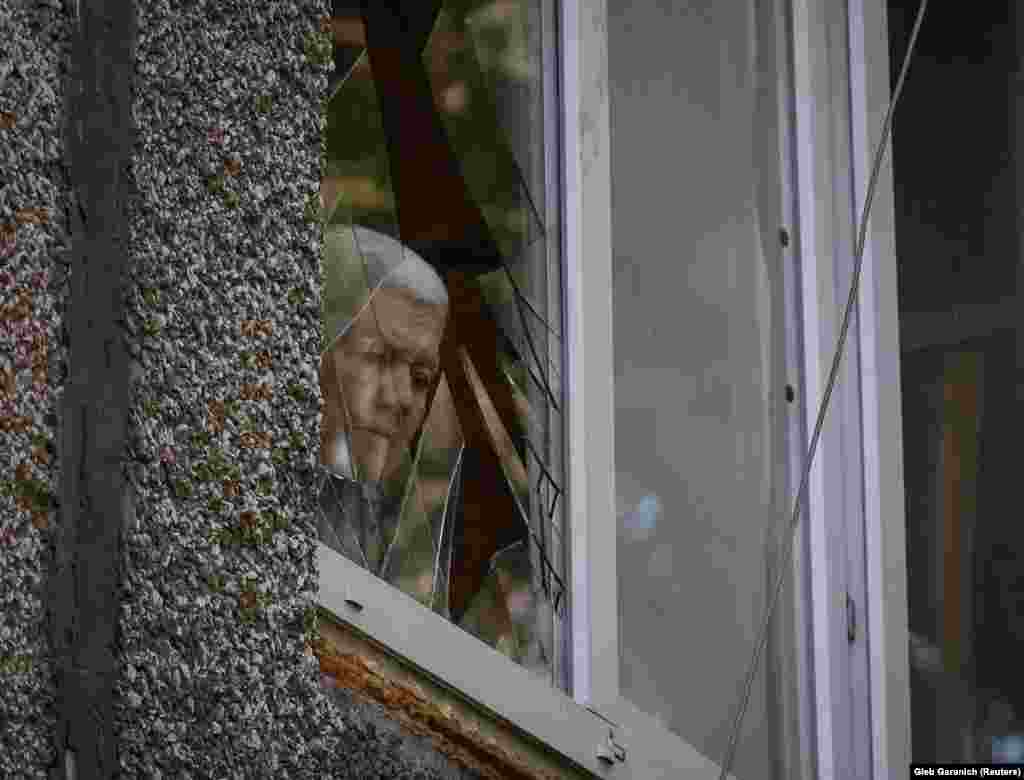 A resident looks through a broken window in a school building damaged by a Russian military strike in the town of Kostiantynivka.