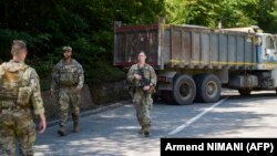 Militari americani din KFOR patrulând lângă un camion sârbesc care bloca șoseaua în apropiere de Zubin Potok, 1 august 2022.