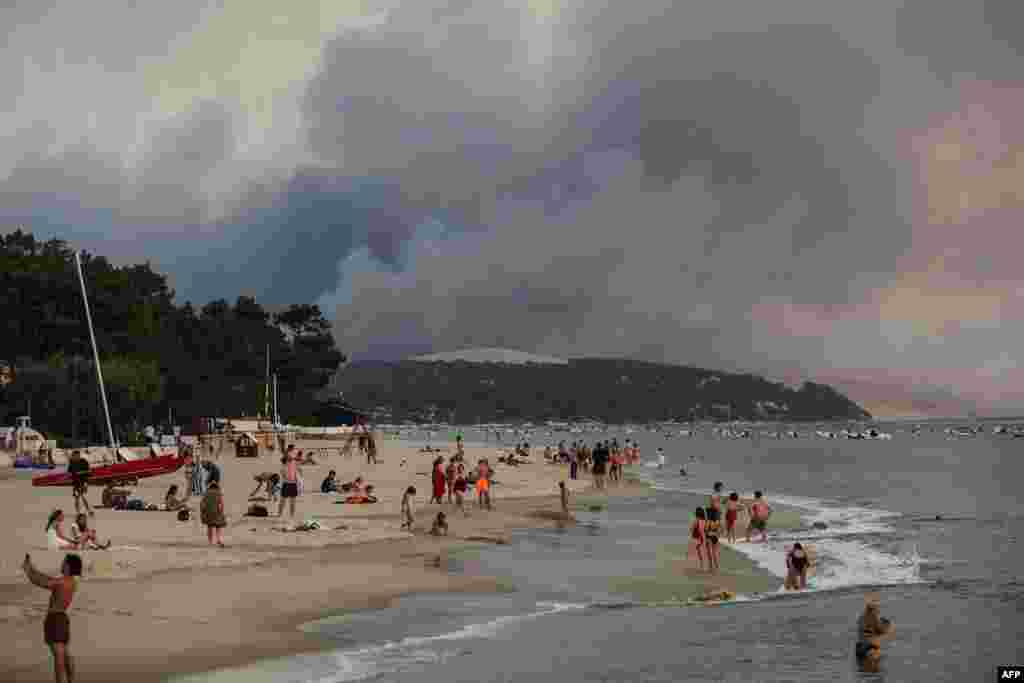 Kupači na plaži Moulleau dok požari bukte u šumi iza u La Teste-de-Buch, 18. juli 2022.