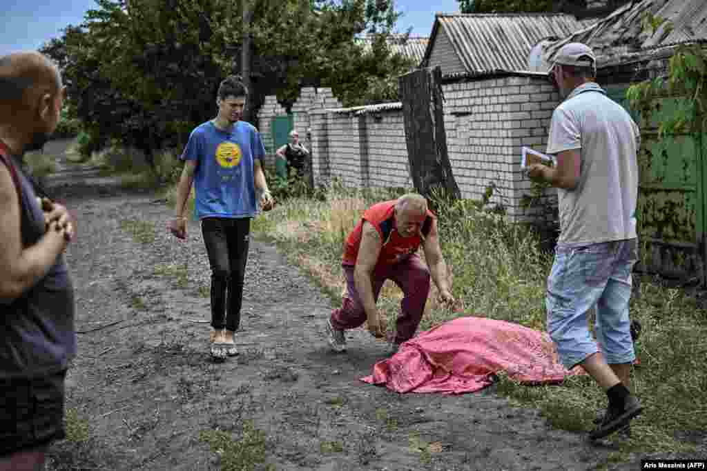 Мужчина бросается к телу своего сына, погибшего при обстреле кассетными бомбами Лисичанска, 18 июня 2022 года.