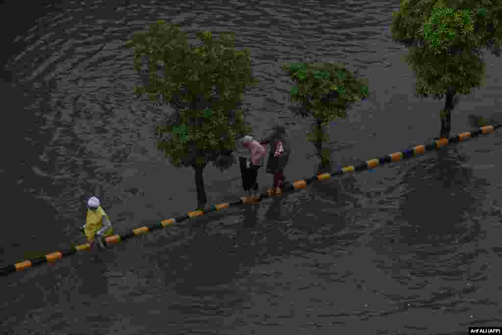Commuters make their way through a flooded street after heavy rain in Lahore, Pakistan.