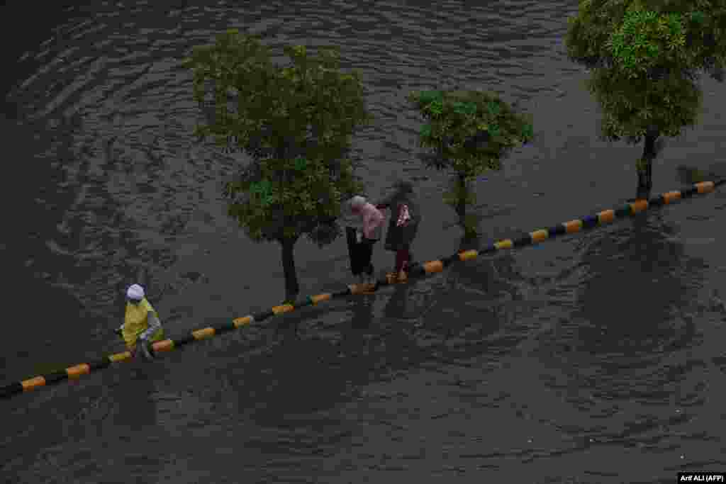 Commuters make their way through a flooded street after heavy rain in Lahore, Pakistan.