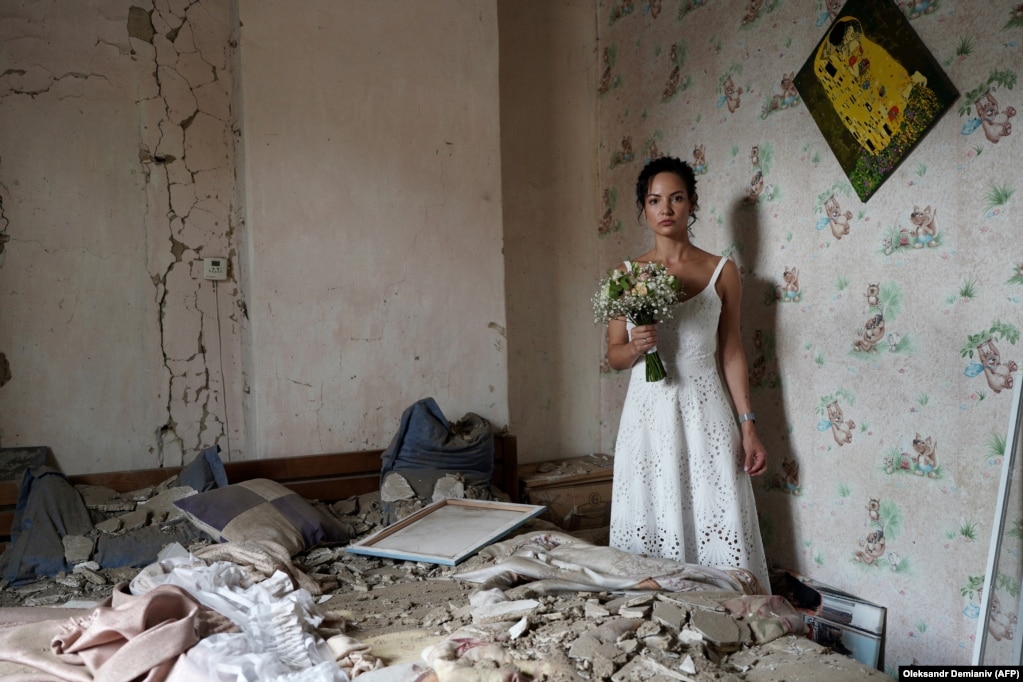 Dariya Steniukova, 31 vjece, pozon për fotot e dasmës në banesën e saj të bombarduar në Vinitsja më 16 korrik. Një raketë goditi qytetin 200 kilometra në jugperëndim të Kievit, një ditë përpara se të bëhej dasma e Steniukovas. “Shtëpia ime u rrënua, por jo jeta jonë”, tha ajo për AFP. "Ishte një mesazh sfidues për të gjithë botën -- duke theksuar se sa të fortë janë ukrainasit. Ne jemi gati të martohemi me gjithë raketat që fluturojnë mbi kokat tona", tha ajo.