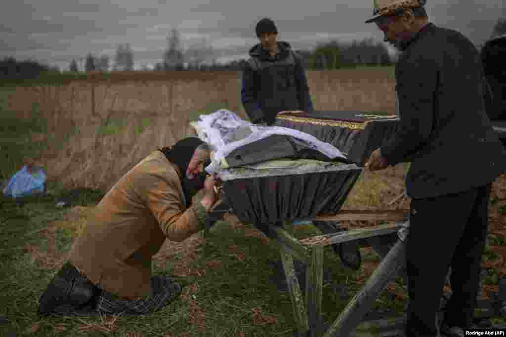 70-летняя Надежда Трубчанинова плачет, держась за гроб своего сына Вадима в Буче, под Киевом, 12 апреля 2022 года. По данным украинских властей, Вадима убили российские военные 30 марта.