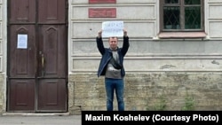 Пикетчик Максим Кошелев у призывного пункта с плакатом "Мир победит"