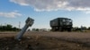 Un camion militar rus trece pe lângă o rachetă neexplodată aflată acolo din timpul conflictului dintre Ucraina și Rusia în satul Ciornobaivka, din regiunea Herson, controlată de Rusia, 26 iulie 2022. 