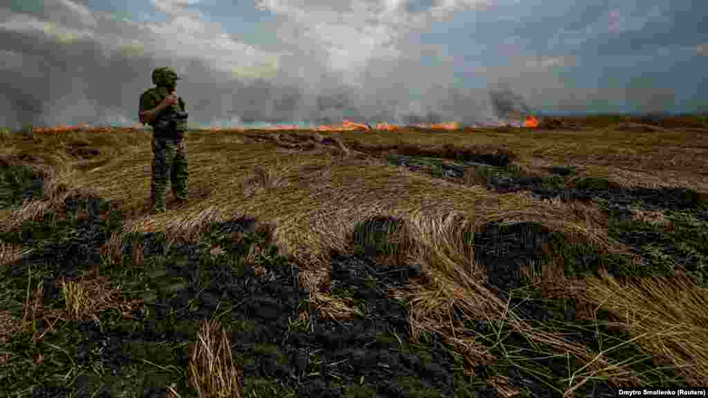 Militar ucrainean pe un lan de grâu arzând la granița dintre regiunile Zaporoje și&nbsp; Donețsk, 17 iulie 2022.