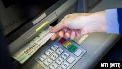 Bankjegyeket vesz ki egy pénzkiadó automatából (ATM) egy ügyfél Budapesten, a Rákóczi úton 2014. március 25-én