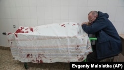 A man cries over his teenage son's lifeless body on a stretcher at a maternity hospital converted into a medical ward during the war with Russia in Mariupol in March 2022.