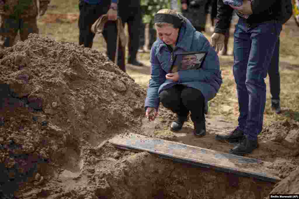 Iryna Tromsa throws soil into the grave of her son, Bohdan, 24, in Bucha on April 23. Bohdan was a Ukrainian paratrooper killed fighting Russian troops in the northeast of his country.&nbsp;