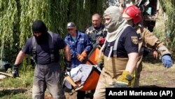 Рятувальники несуть тіло загиблої внаслідок російської атаки Чугуєва, 26 липня 2022 року 