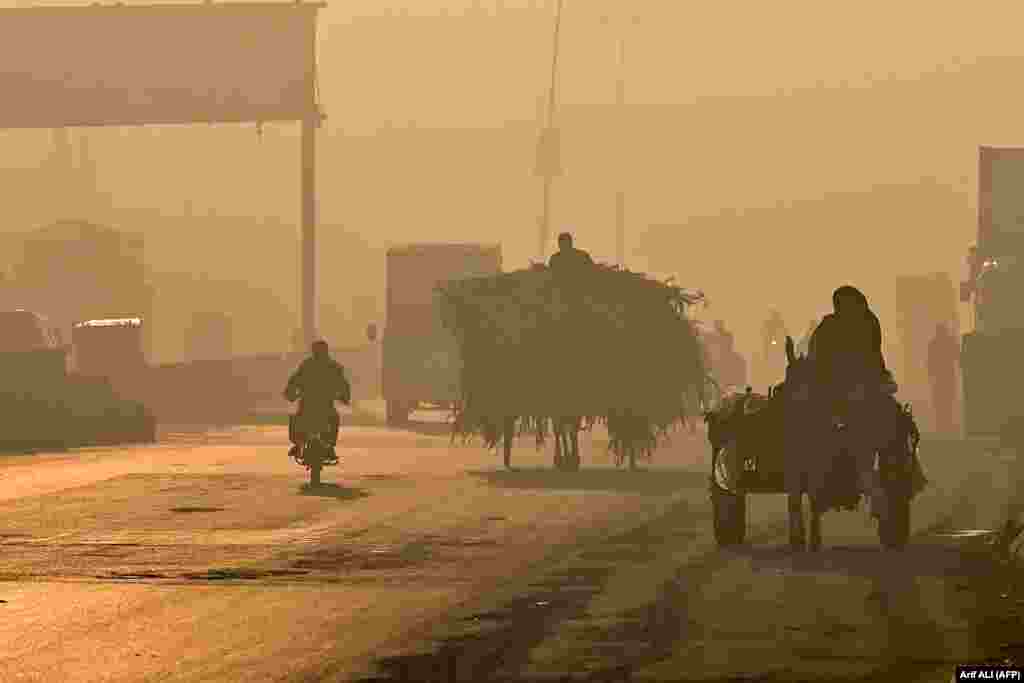 Disa udhëtarë pakistanezë duke ecur në një rrugë mes smogut të rëndë në Lahore.