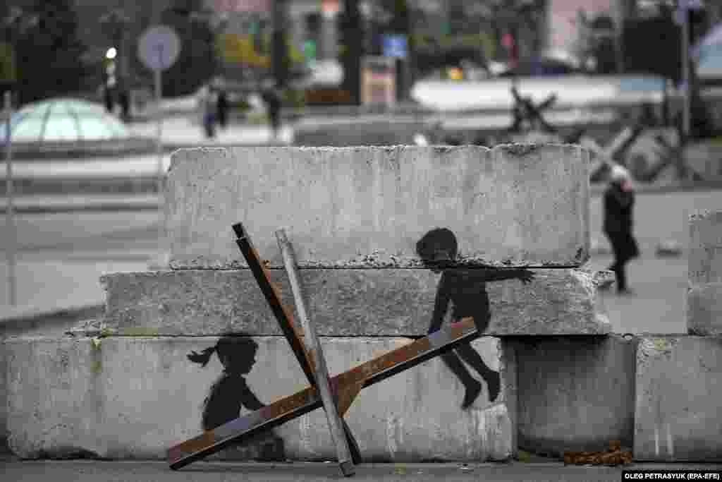 People walk past street art on concrete blocks in Kyiv&#39;s Independence Square.